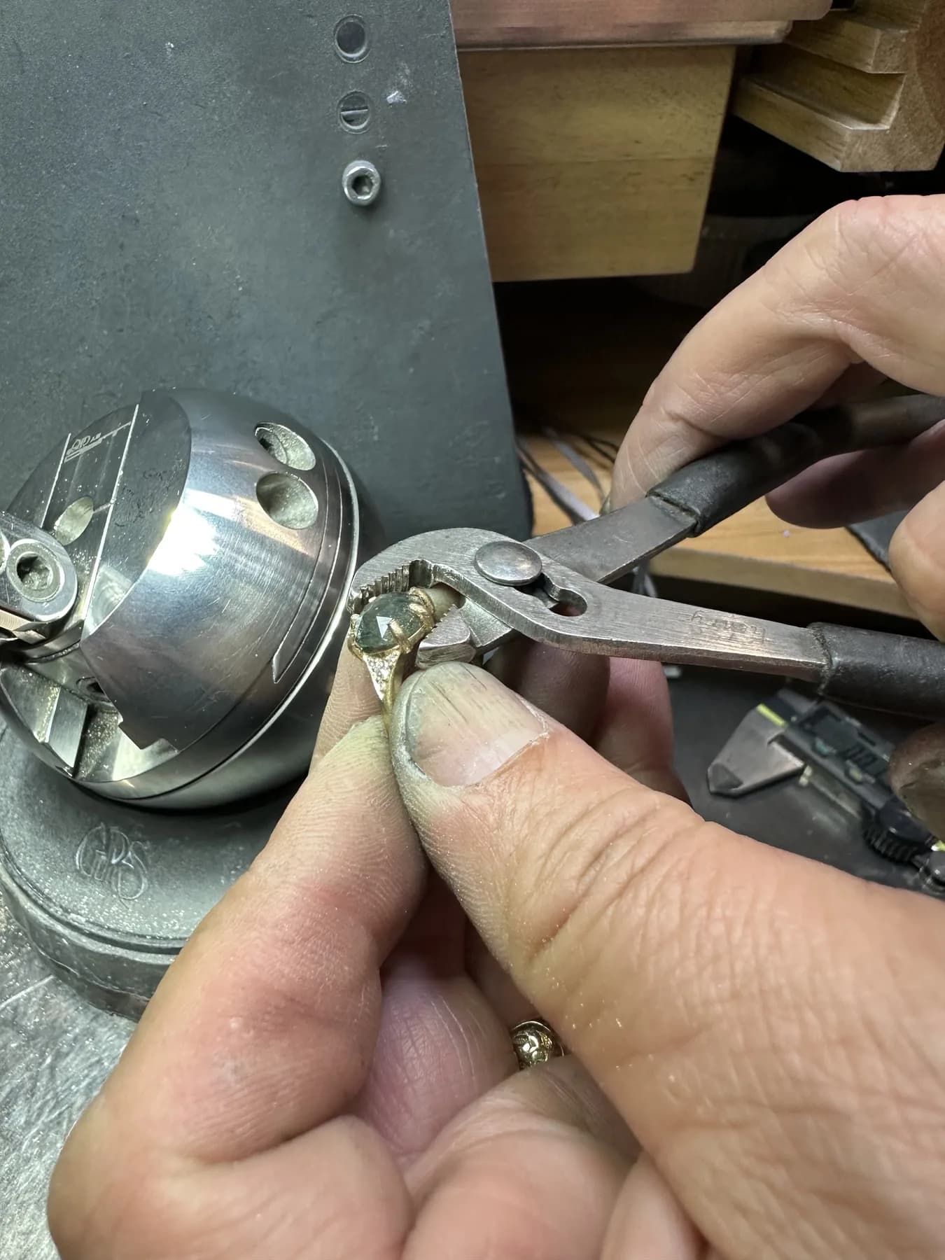 Jeweler adjusting the prongs around a green gemstone